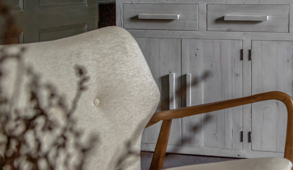 Armchair and wooden table with drawers with ornaments on it