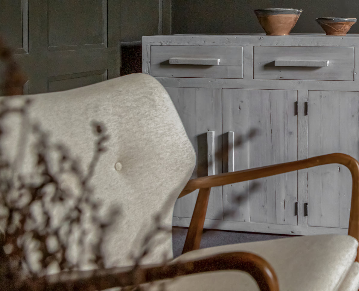 Armchair and wooden table with drawers with ornaments on it