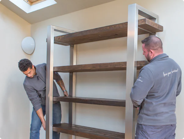 Eat, Sleep, Live employees fitting wooden shelving in a house
