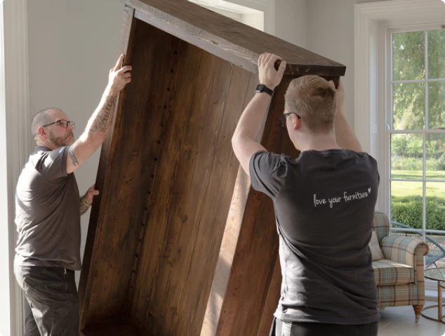 Eat, Sleep, Live colleagues lifting a wooden wardrobe