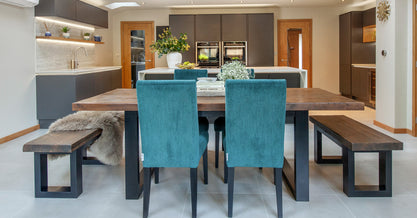 Dining table in a kitchen/diner with wooden benches and suede teal dining chairs