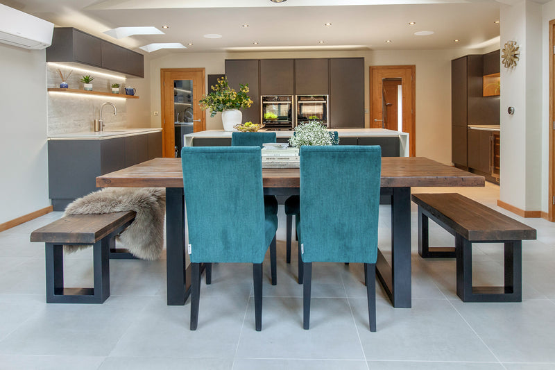 Dining table in a kitchen/diner with wooden benches and suede teal dining chairs
